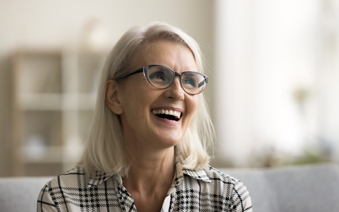 smiling older woman on a couch, smiling showing dental veneers