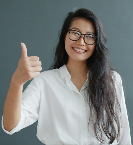 Smiling cosmetic dental patient with black hair and glasses shows off nice teeth for a picture in Florence, KY giving a thumbs up